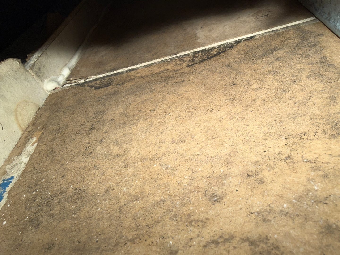 Close-up of a borescope camera cable near a tile floor and baseboard corner