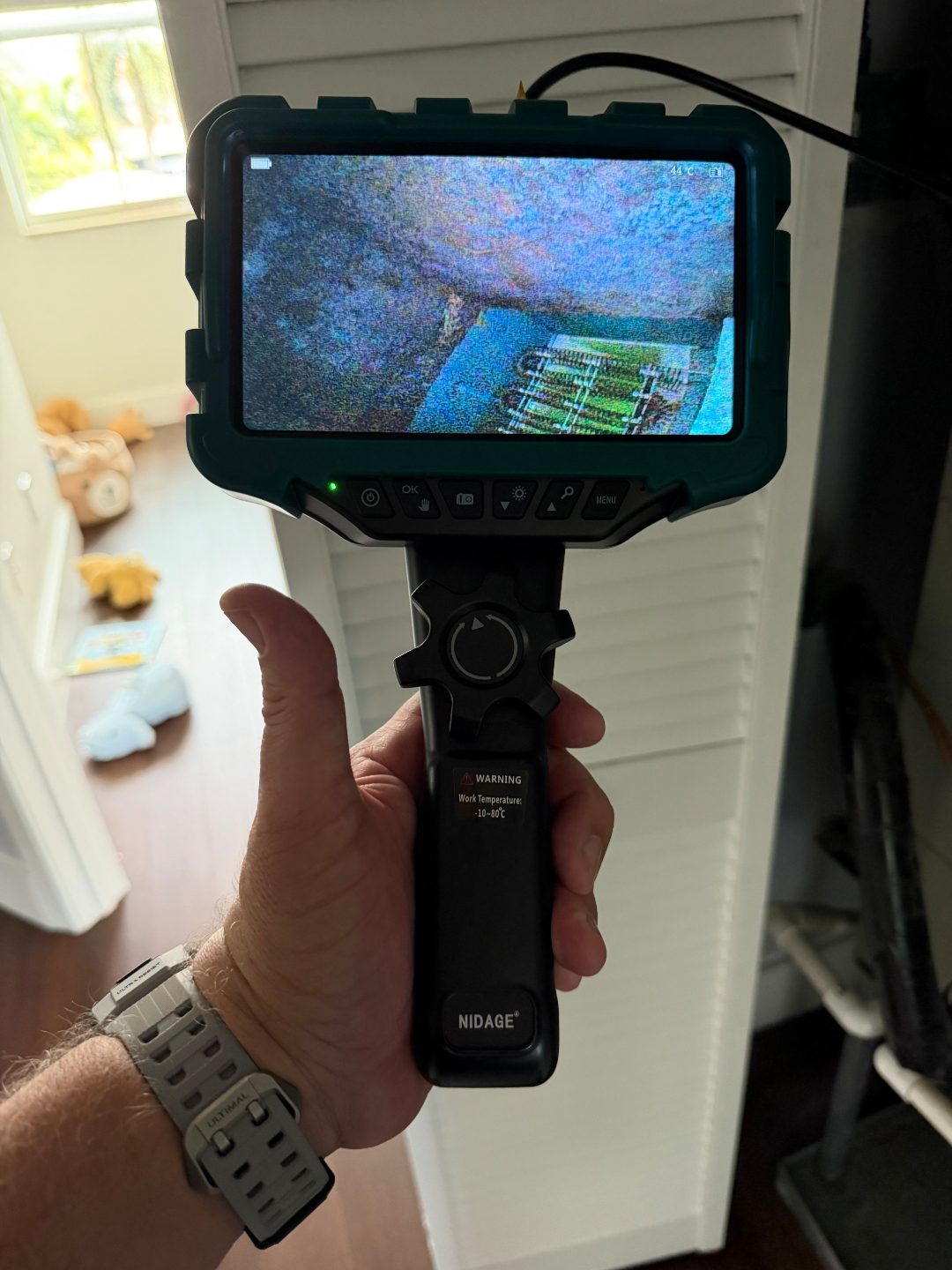 Hand holding a borescope camera near a closet door, a third angle of the same coil pattern scan