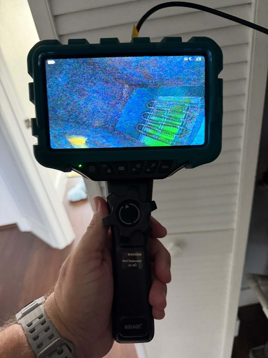 Hand holding a borescope camera near a closet door, a fifth angle of the same coil pattern scan